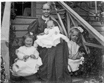 Woman seated on steps with three small children, c. 1912