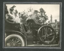 People in touring attire seated in automobile