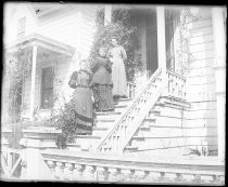 Three women posing on steps of Victorian home