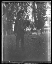 Young man in suit posing in grove of trees