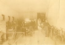 Bruce Maxwell inside of bicycle shop with two men