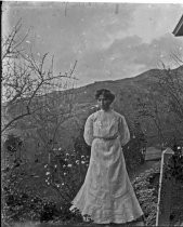 Woman in white dress, hills behind her, c. 1912