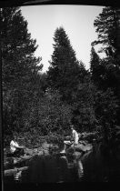 Two women seated on rocks in river