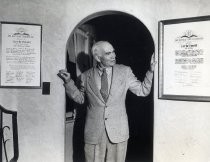 Lee de Forest in doorway at home, between framed awards