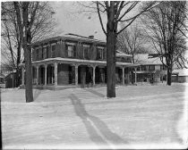 Two-story brick house with wrap-around porch in winter, c. 1912