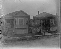 Two, one-story Victorian homes on a street with incline, c. 1912