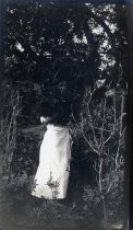 Woman in white skirt posing next to tree