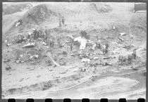 Men and hoses near wreckage on beach