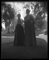 Two women posing on manicured lawn with walkways, c. 1900