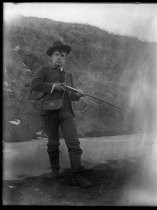 Man posing with rifle outdoors