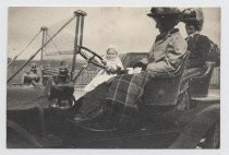 Two women seated in automobile with an infant at the wheel