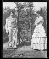 Two women dressed for Fiesta de las Rosas, posing with trellis