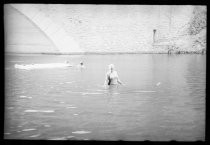 Swimmer in bathing cap under stone arch bridge