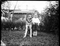 Young boy with his German Shepherd dog, outside in grassy yard