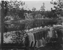 Water over small dam, with rocky cliffs, c. 1912