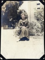 Young woman in school uniform seated on fence