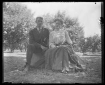 Couple seated on bench in front of orchard