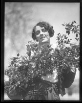 Woman dressed for Fiesta de las Rosas, posing with blossoms