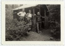 Three boys standing next to shed