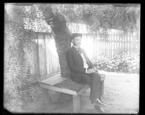 Man in suit seated under willlow tree