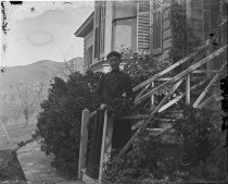 Woman on steps of house, orchard in background, c. 1912