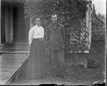 Man and woman in front of rustic house, c. 1912