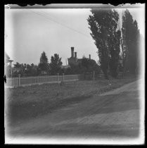 Dirt road, fence, and buildings in distance