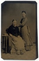 Portrait of two women, seated and standing, with books