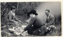 Harold Elliott with two women around a campfire