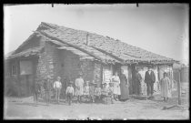 Large family in front of adobe building with tile roof