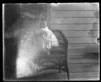 Infant standing on wicker chair on porch