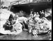 Group outdoors on rocks, with bridge behind