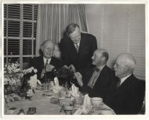 Four men at dinner table with bowl of cherries