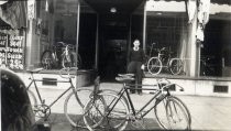 Man posing in front of Maxwell's Bicycle Shop