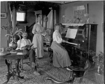 Relaxing in the parlor with piano and book, c. 1912