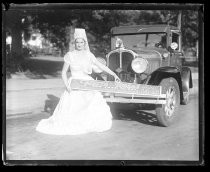 Woman holding Fiesta de las Rosas sign in front of car