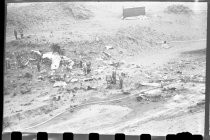 Men and hoses near wreckage on beach