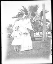 Woman with two small children, in park with palms