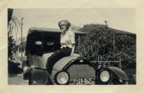 Young woman seated on top of automobile, c. 1920