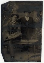 Portrait of two men, one seated on a bench