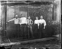 Group portrait with water hose outside house, c. 1912