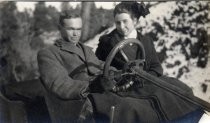 Man and woman at wheel of automobile