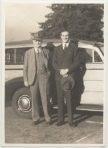 Two men in suits standing in front of station wagon