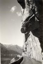 Road curving through rock face, with mountains in distance