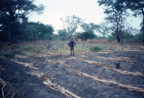 Farmer posing with his garden that has been prepared for planting, but waiting on the start of the rainy season, Kaputa village