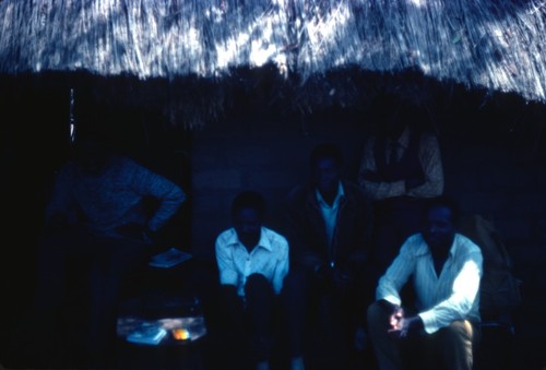 Group of men in the shade of a veranda during a storytelling session in Kaputa village