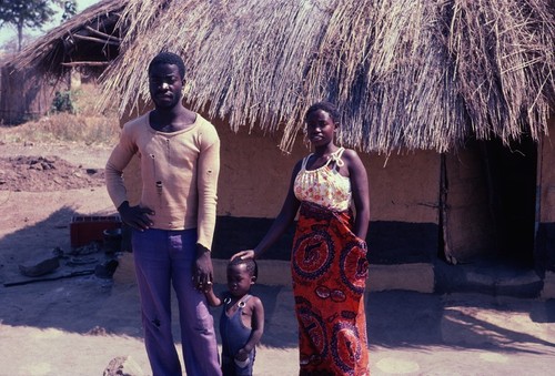 Daughter of Paul Nsama with her family in front of their home, Nsama village