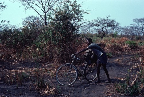 Young man using a bicycle to transport a bag of salt near the salt-making camp near Kaputa village