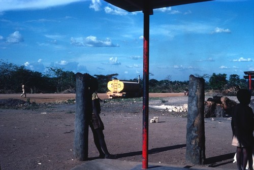 Water Tank Truck of Stanley Associates Road-Building Team as seen from a shop's porch at Kaputa village