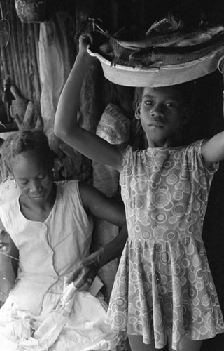 Girl standing with bowl of fish on her head, San Basilio de Palenque, 1975